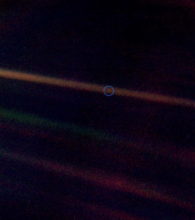 This is the "Pale Blue Dot" photograph of the
Earth taken by the Voyager 1 spacecraft on July 6, 1990. The Earth is the relatively
bright speck of light about halfway across the uppermost sunbeam. (shown here inside a
blue circle)